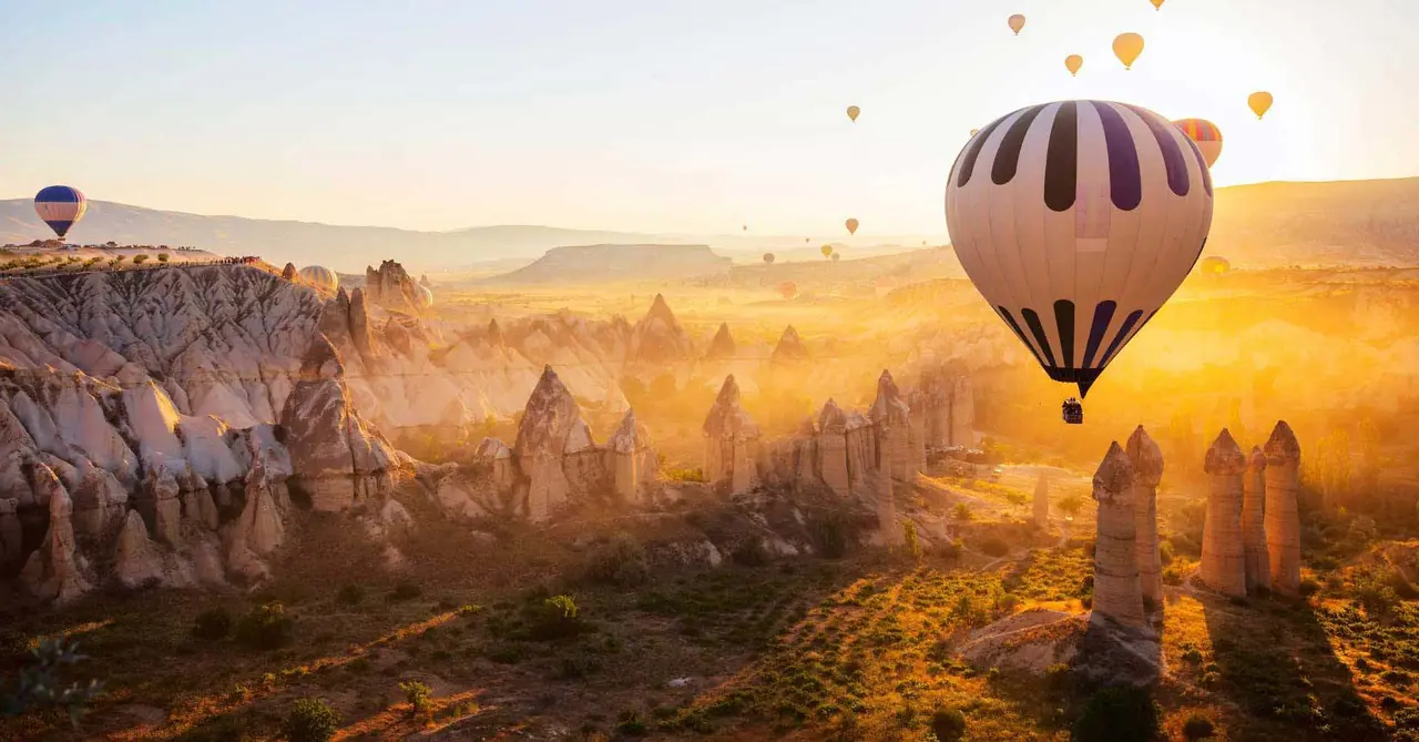 Hot air balloons flying over fairy chimneys at sunrise in Cappadocia