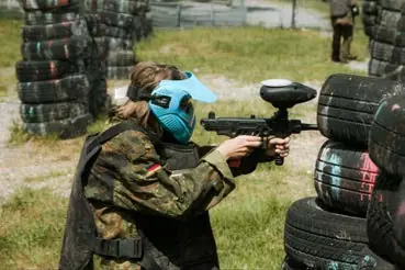 A player in a helmet taking aim with a paintball gun