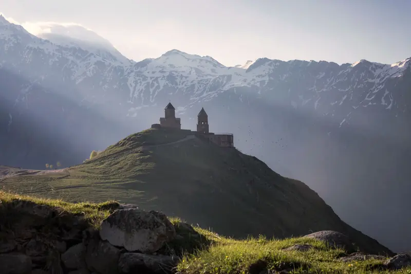 Kazbegi'de tepe üzerindeki Gergeti Trinity Kilisesi ve Kafkas Dağları